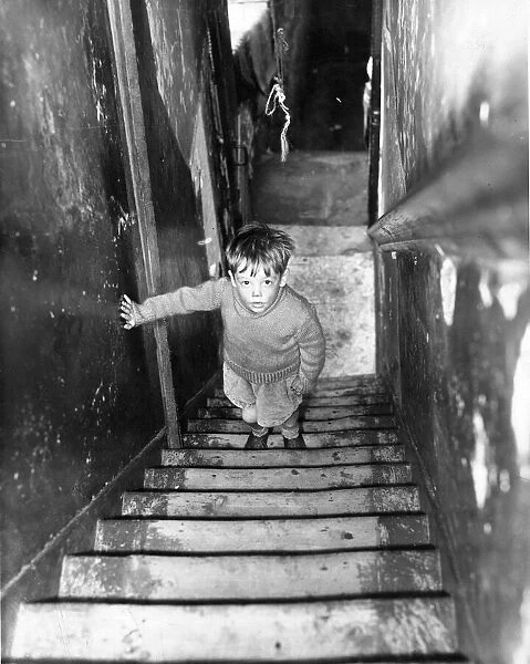 The Interior of slum housing in an area of Newcastle - A dirty child climbing the stairs