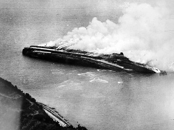 The Italian liner Rex lies on her side blazing after being destroyed by Allied bombers