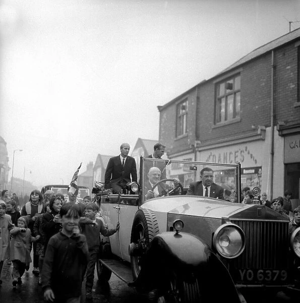 Jack and Bobby Charlton look over-awed as youngsters crowd around the car taking them to