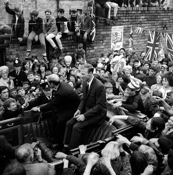 Jack and Bobby Charlton look over-awed as youngsters crowd around the car taking them to
