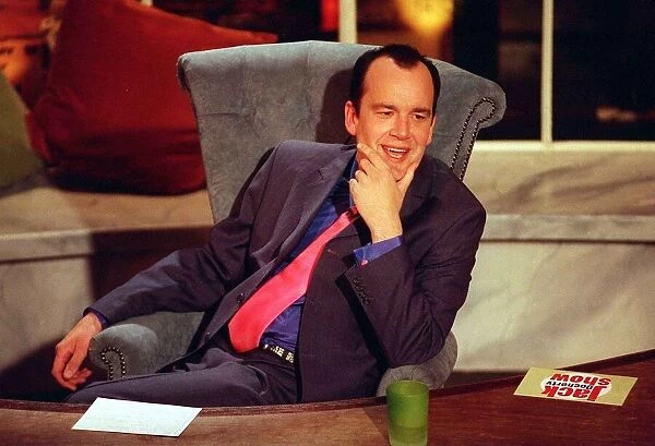 Jack Docherty sitting in chair next to desk in Channel 5 studio April 1997