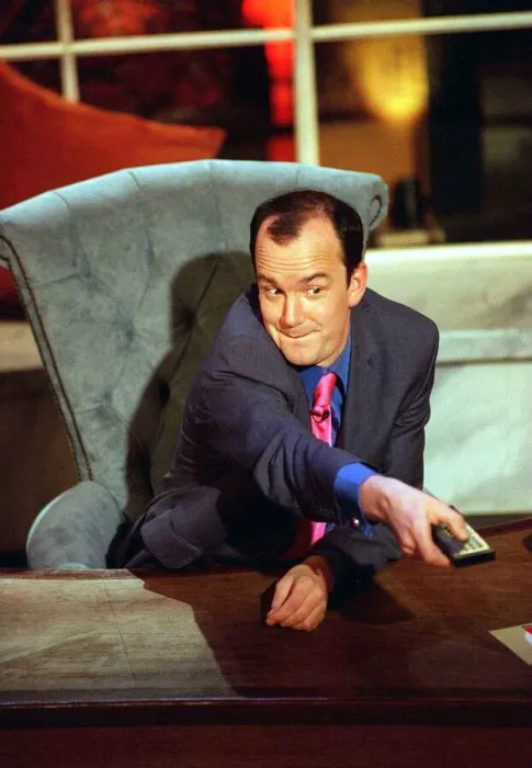 Framed Print : Jack Docherty sitting in chair left hand on desk right hand pressing television remote Framed Print : Jack Docherty sitting in chair left hand on desk right hand pressing television remote
