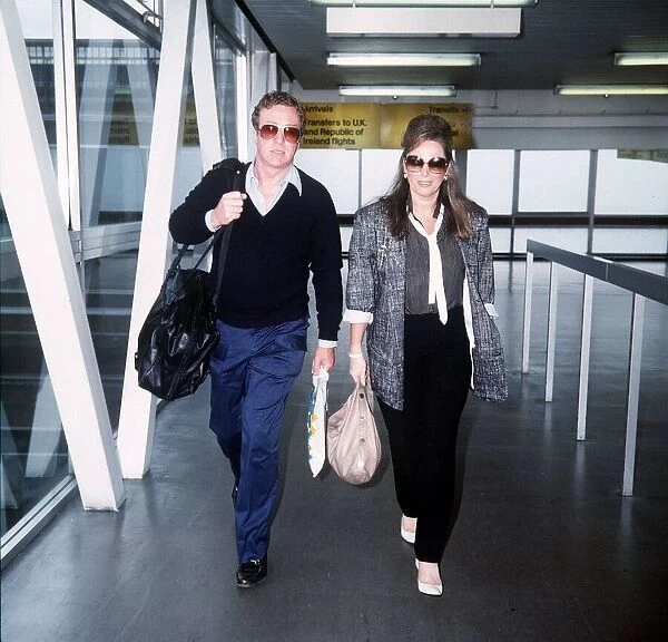 Jackie Collins Writer walking through Heathrow airport with Michael Caine