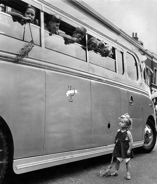 Jacqueline Gordon aged 3, standing by a school bus full of children. July 1952