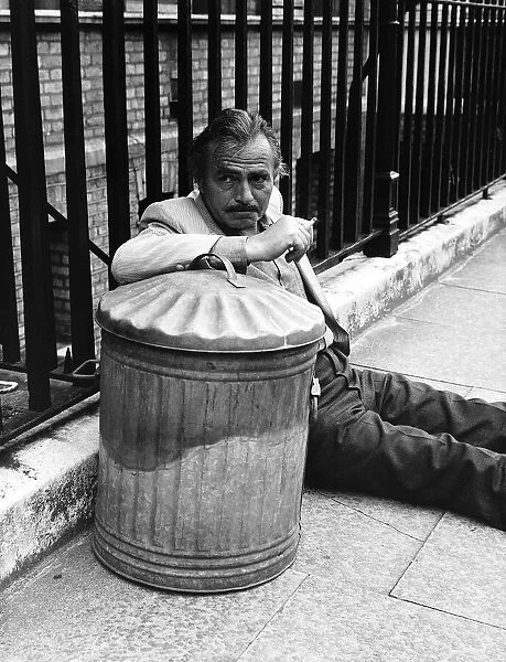 James Mason Actor leaning on a dustbin and fence