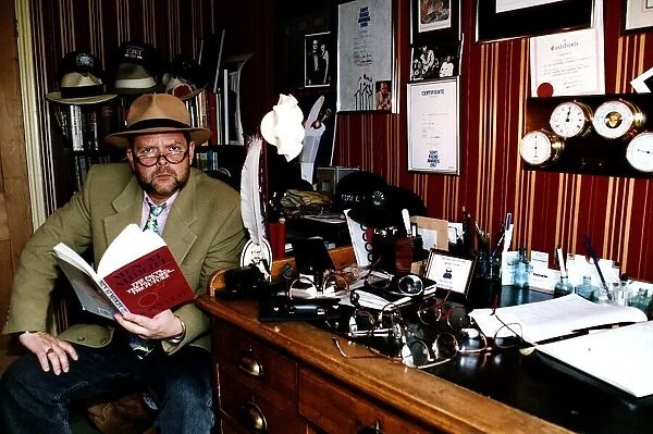 James Whale TV and Radio Presenter Sitting at desk holding book