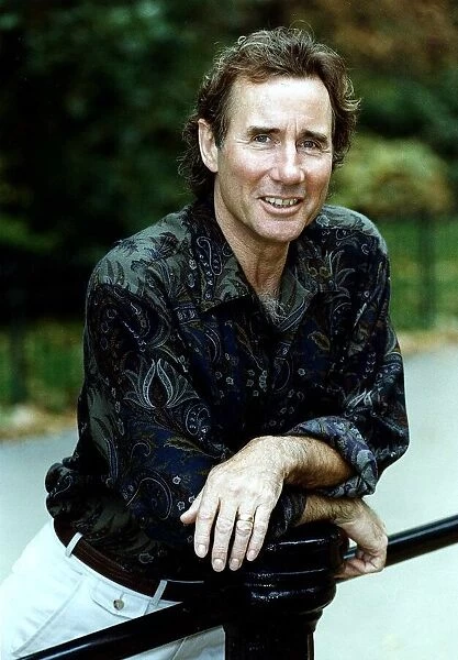 Jim Dale British Comedy Actor wearing patterned shirt leaning on metal railing
