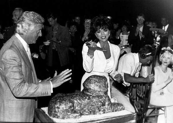 Joan Collins Actress frowning at cutting the cake in the shape of a Sphinx