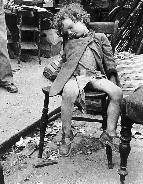 Joan Smalls sleeping in the London street while her mother clears up the bomb damage to