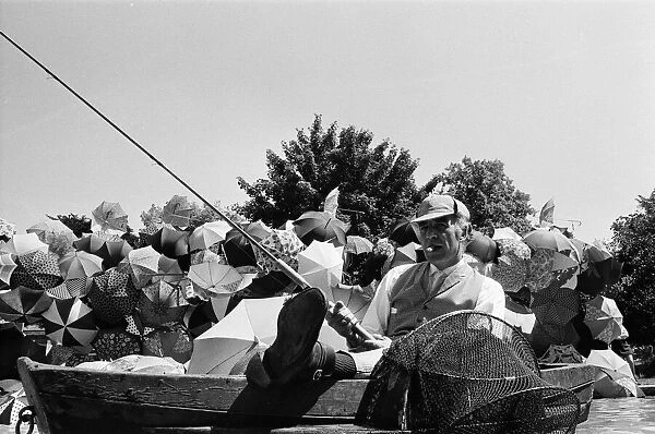 Joe Carver, owner of an umbrella making business, sitting in a fishing boat smoking a