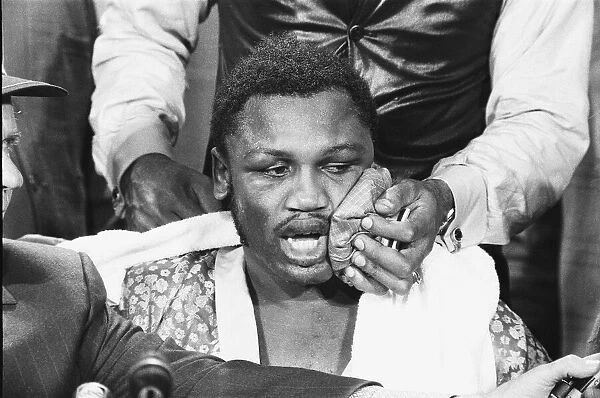 Joe Frazier seen here giving a press conference whilst an aide applies a ice bag to his