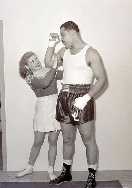 Joe Louis with female model cheerleader feeling the size of his bicep at Earls Court