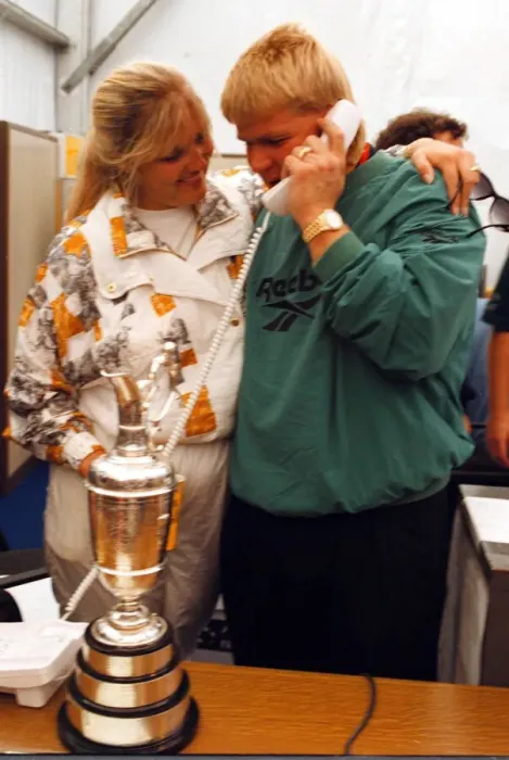 Framed Print : John Daly phones home to his parents in the USA watched by his wife Paulette after