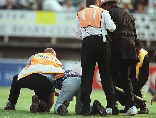 John Holder umpire is helped by steward after he was knocked to the ground by a fan at