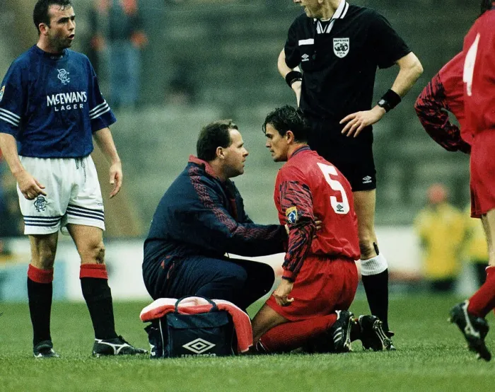 Framed Print : John Inglis of Aberdeen kneeling on ground being treated by a physio after a headbutt by