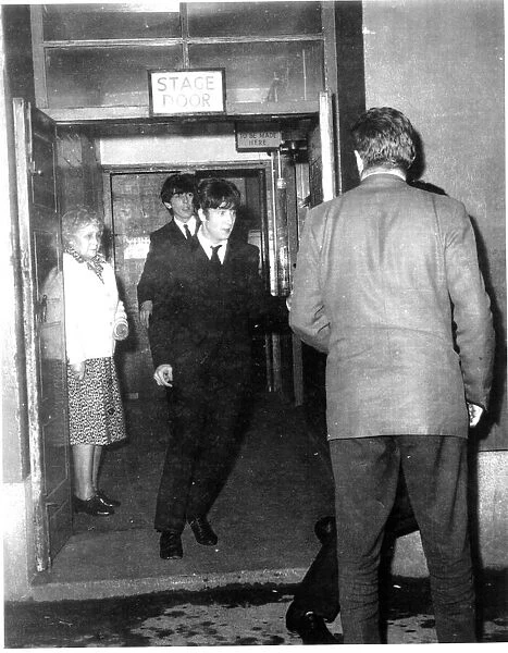 John Lennon and George Harrison make their way through the stage door after