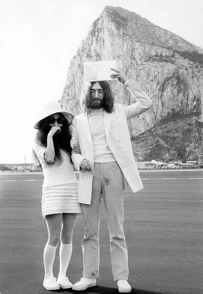 John Lennon holds his marriage certificate above his head as he stands with his new wife