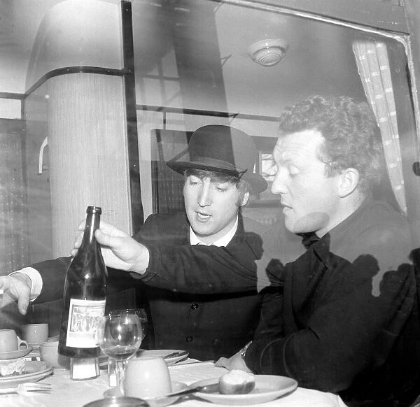 John Lennon wearing a bowler hat and smoking a cigarette at a dining table on the train