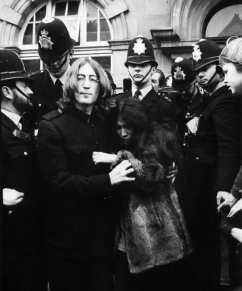 John Lennon with Yoko Ono surrounded by policemen as they leave Marylebone Magistates