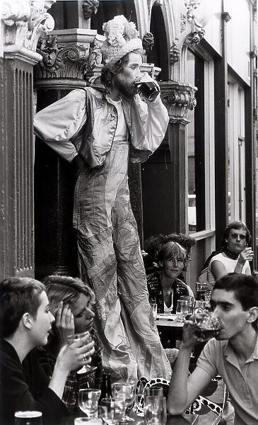John Trigger stilt walker stops for a pint of beer in Covent Garden