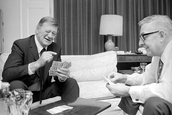 John Wayne pictured relaxing playing cards in his suite at The Connaught Hotel, Mayfair