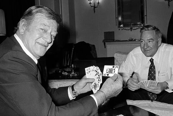 John Wayne pictured relaxing playing cards in his suite at The Connaught Hotel, Mayfair