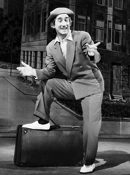 Johnny Beattie comedian comic actor on stage foot on suit case pointing back drop