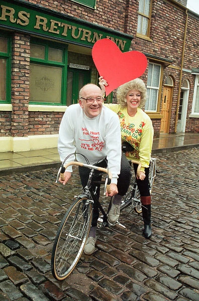 Julie Goodyear and Roy Barraclough pictured on a tandem bike on the set of Coronation