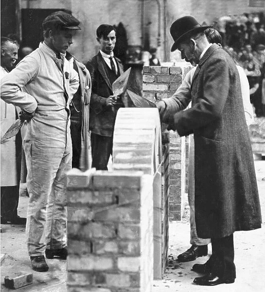 King George V tries his hand at brick laying during a visit to the Government