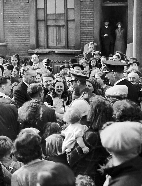 King George VI meets people on a walk-about during a visit to a bomb damaged street in