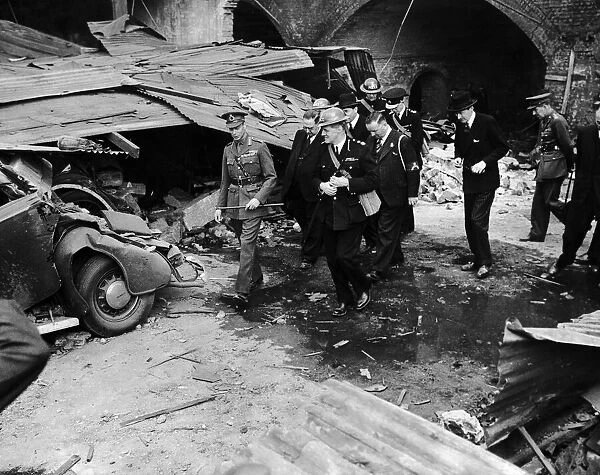 King George VI walks past a wrecked car on a walkabout in the East End of London