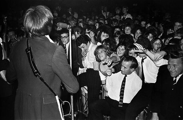 The Kinks on stage, singing to a large crowd September 1964