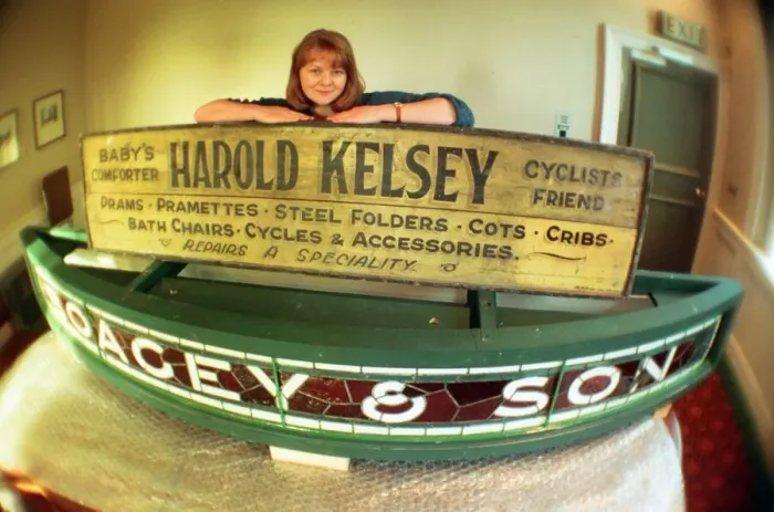 Framed Print : Kirkleatham Old Hall Museum curator Leigh Lampard with two of the old shop signs