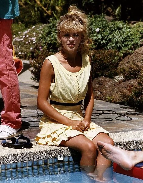 Kylie Minogue in the TV programme set of Neighbours, were she is sitting besides the pool