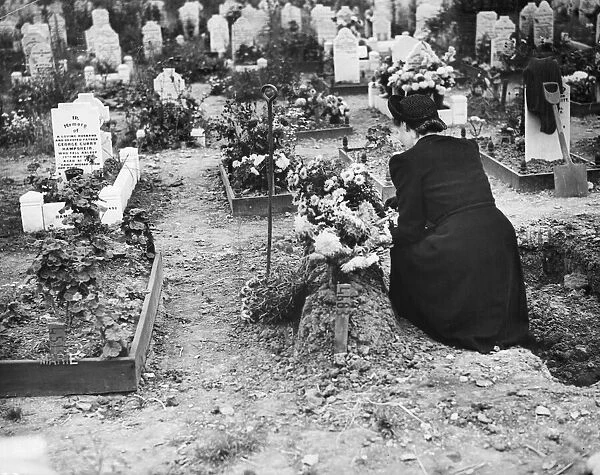 A lady at a graveside of a child who died during an air raid