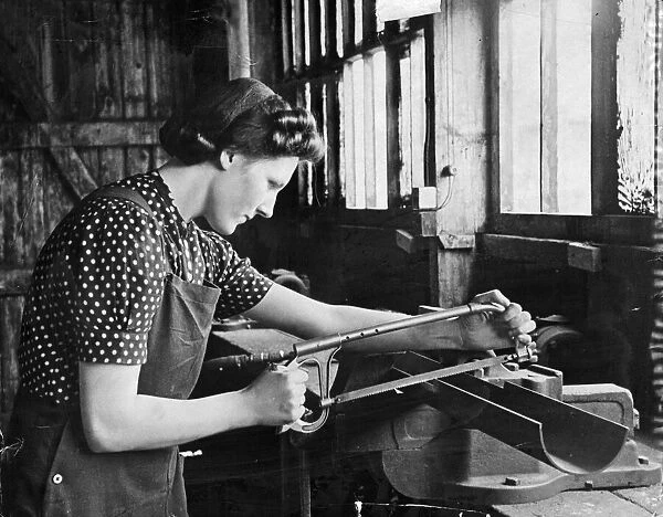 A lady working in a munitions factory. She is using what looks to be a bow saw