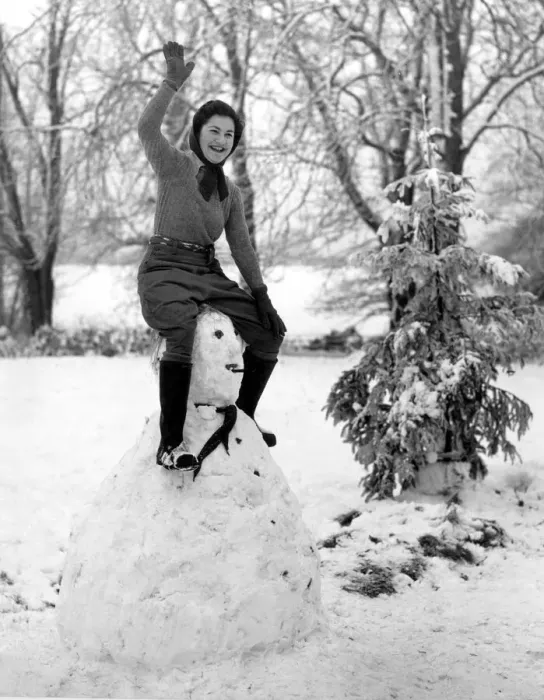Framed Print : A land army girl in Sussex sitting on top of her Hitler snowman during the Second World Framed Print : A land army girl in Sussex sitting on top of her Hitler snowman during the Second World