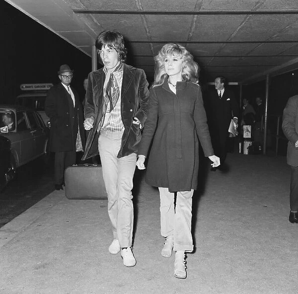 Lead singer of The Rolling Stones pop group Mick Jagger is met by Marianne Faithful at