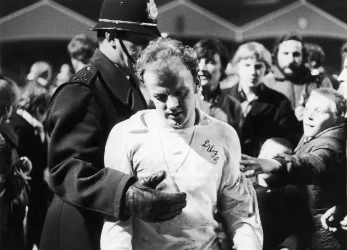 Framed Print : Leeds captain Billy Bremner leaves the field on the consoling arm of the law after his