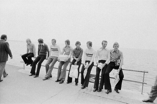 Leeds United players sit on a railing on the promenade as they take a walk around