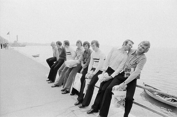 Leeds United players sit on a railing on the promenade as they take a walk around