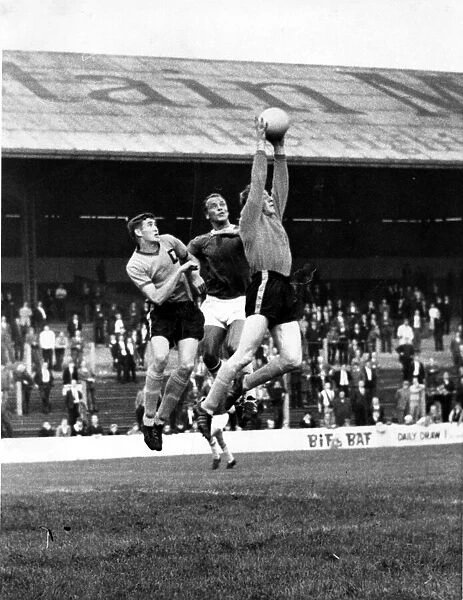 Len Weare, the Newport County goalkeeper jumps high to gather the ball under pressure