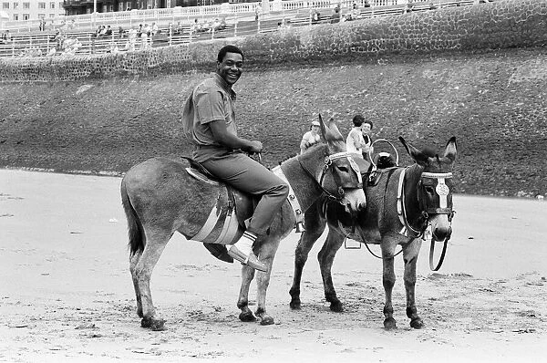 Lenny Henry riding a Donkey at Blackpool Beach, Lancashire. 15th July 1984