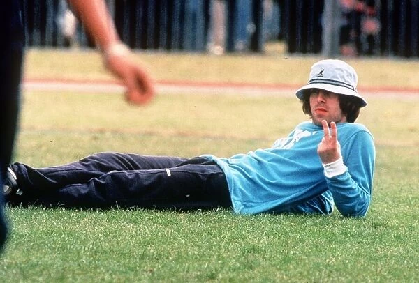 Liam Gallagher of pop group Oasis gives the v sign as he lies on the grass during a