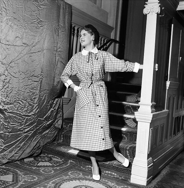 Linda Leigh Fashion Show. Woman poses by the stairs wearing a long check patterned dress