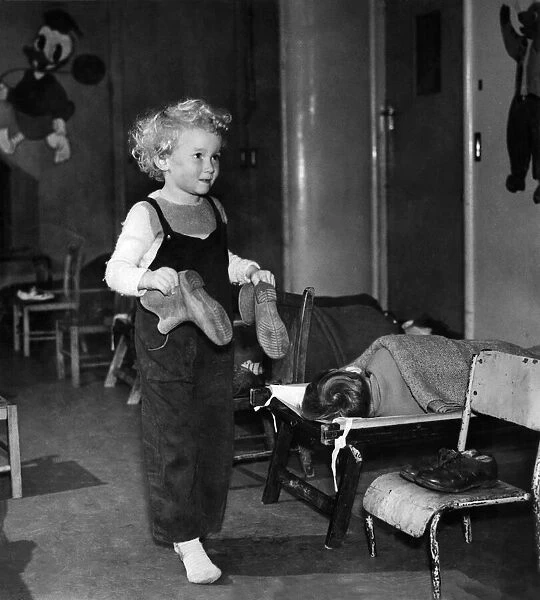 Little 4 years old Leslie Gees with boots in hand goes tiptoe past the line of sleeping