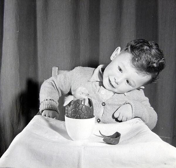 Little boy with chick in chocolate Easter egg. Circa 1960