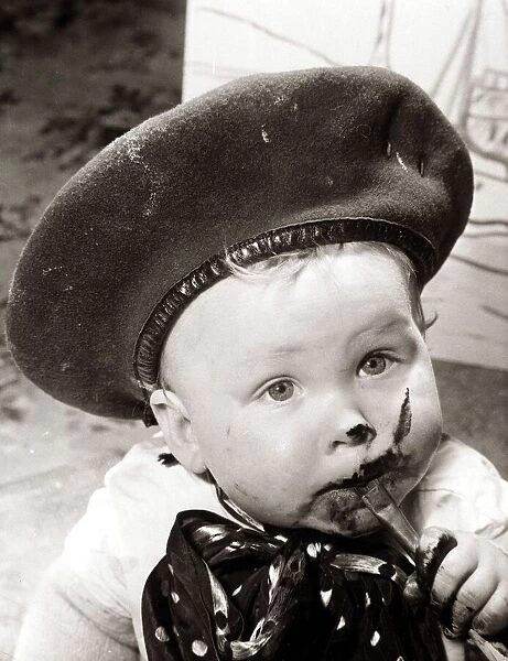 Little boy, eating chocolate in a very messy way. Circa 1950