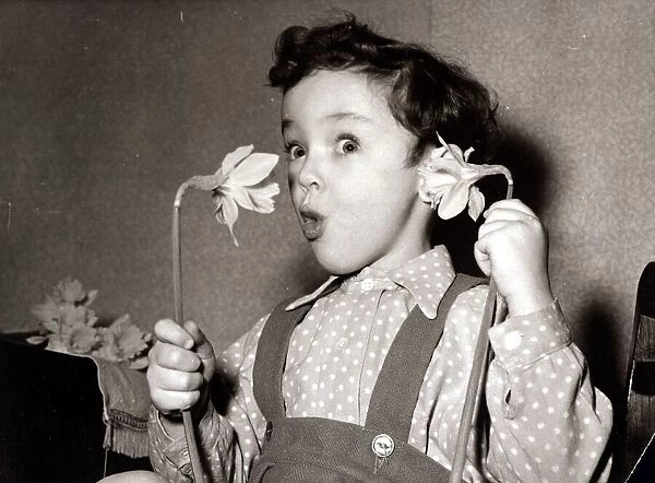 Little boy, Paul, hold flowers daffodils up to his ear and mouth like a telephone