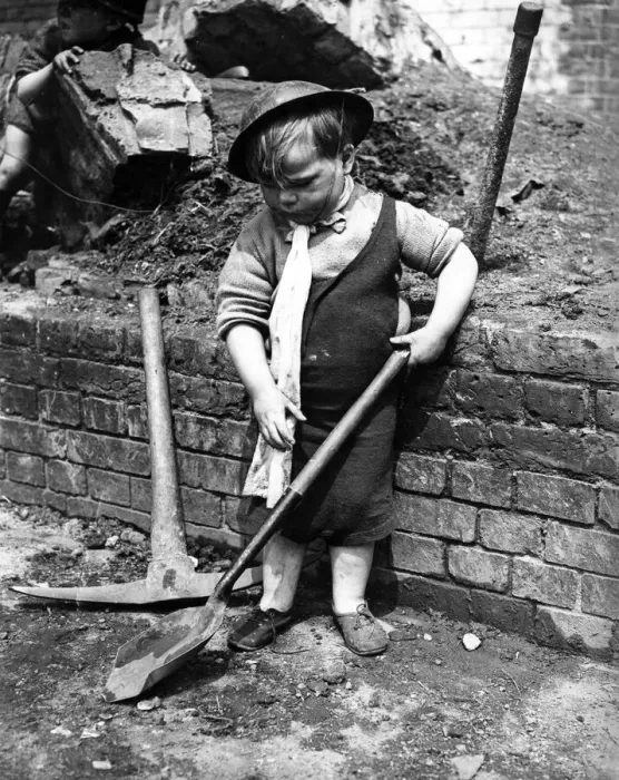 Framed Print : A little boy pays with a shovel following air raid attacks in England. Circa 1941 Framed Print : A little boy pays with a shovel following air raid attacks in England. Circa 1941